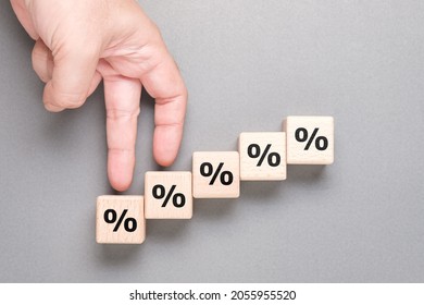 Closeup hand gesture as fingers walking step up on the wood cubes with percentage symbol, commission increase, insurance, and savings - Shutterstock ID 2055955520
