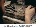 Close-up of a hand of a goldsmith who builds a precious jewel with valuable diamonds. To make the jewel it takes: precision, craftsmanship and patience. Concept of: gold, luxury.