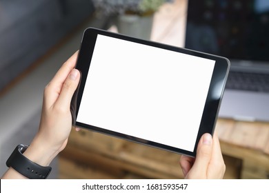 Close-up Of Hand Holding Black Tablet On Sofa In Living Room.