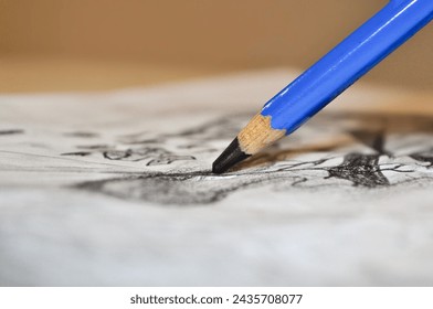 Close-up of a hand holding a blue pencil, drawing or sketching on a piece of paper. - Powered by Shutterstock