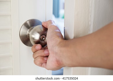 Close-up hand holding door knob, opening door slightly, selective focus - Shutterstock ID 417535024