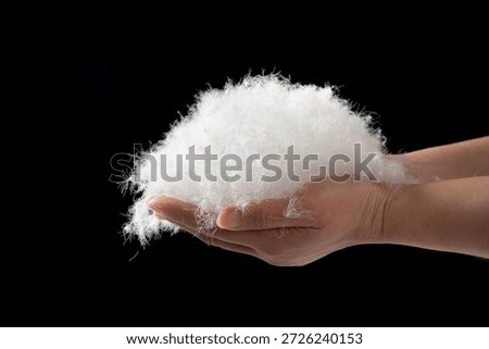 closeup of hand holding down feather on black background
