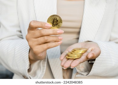 Closeup of hand holding golden bitcoin, advertising coin, copy space for cryptocurrency commercial, digital money, electronic investment. Cropped portrait of businesswoman holding bitcoin and showing