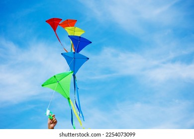 Close-up of a hand holding group of colorful kites over blue sky - Powered by Shutterstock