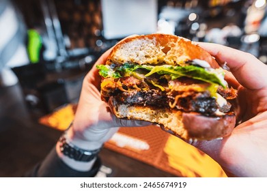 Close-up of a hand holding a half-eaten burger with lettuce and tomato, showcasing a casual dining experience. - Powered by Shutterstock