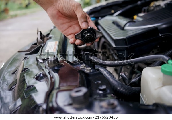 Close-up of\
a man’s hand holding the lid and opening the radiator to check the\
status of the cooling system. man’s hand open the radiator cap to\
check the water level of the car\
radiator.