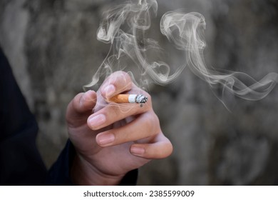 Closeup hand holding lighted cigarrette of asian smoking boy in private area of school and house to avoid punishment from teachers or parents, new edited. - Powered by Shutterstock