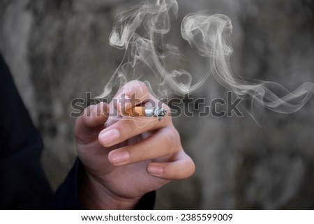 Closeup hand holding lighted cigarrette of asian smoking boy in private area of school and house to avoid punishment from teachers or parents, new edited.