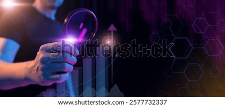 A close-up of a hand holding a magnifying glass, focusing on a glowing upward graph with a target at its peak. The futuristic neon-lit scene symbolizes business growth, success, and goal achievement