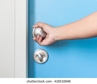 Closeup Of Hand Holding Metal Silver Doorknob On Wooden Door