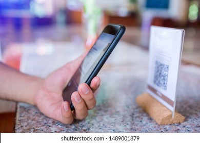 Closeup of a hand holding phone and scanning qr code. Man hand paying with qr code. Customer hand making payment through smart phone and scan code. Selective focus