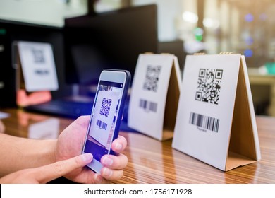 Closeup of a hand holding phone and scanning qr code. Man hand paying with qr code. Customer hand making payment through smart phone and scan code. Selective focus.