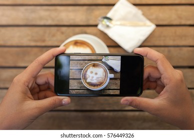 Close-up Hand Holding Phone Taking Coffee Photo On Table