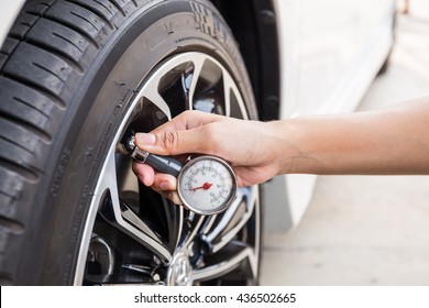 Close-Up Of Hand holding pressure gauge for car tyre pressure measurement
