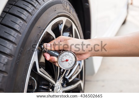 Close-Up Of Hand holding pressure gauge for car tyre pressure measurement