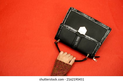 Closeup Hand Holding Shoulder Bag Isolated On Red Background 