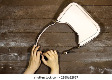 Closeup Hand Holding Shoulder Bag On Wood Table 