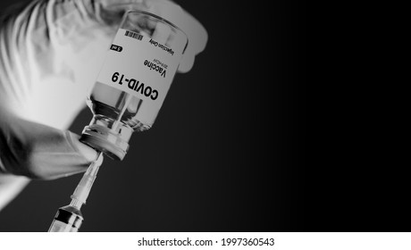 Closeup of hand holding syringe and COVID-19 vaccine.dark tone immage.
