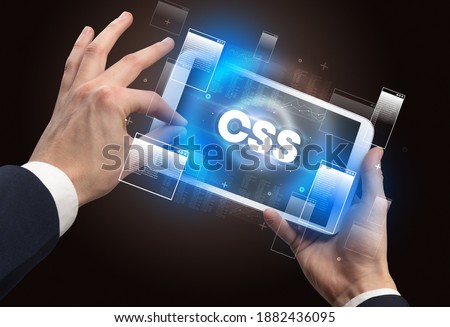 Close-up of a hand holding tablet with CSS abbreviation, modern technology concept