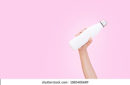 Close-up Of Hand Holding White Reusable Steel Thermo Water Bottle Isolated On Pink Background With Copy Space.