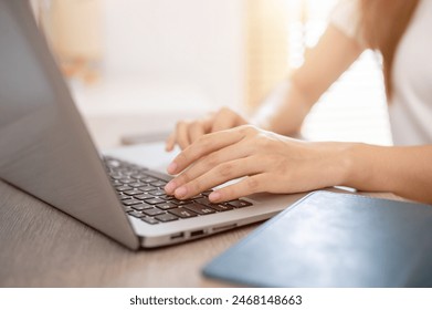 A close-up hand image of a woman working on her laptop computer, typing on the laptop keyboard, surfing the net at home, working from home. people and technology concepts - Powered by Shutterstock