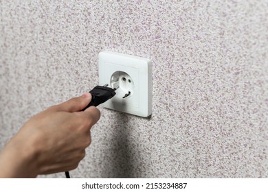 Close-up Of A Hand Inserting A Black Plug Into A White Socket.