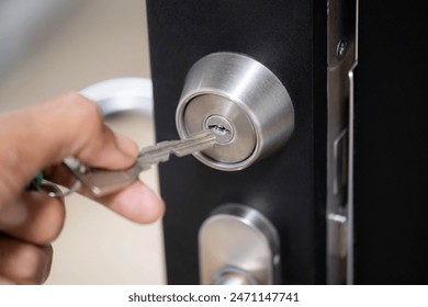 Close-up of a hand inserting a key into a door lock. - Powered by Shutterstock