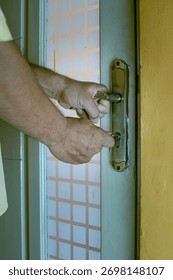 Close-up of a hand inserting a key into an old rusty door lock, symbolizing security, access, and safety concepts, in portrait 