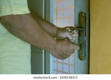 Close-up of a hand inserting a key into an old rusty door lock, symbolizing security, access, and safety concepts, landscape