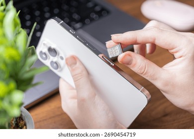 Close-up of a hand inserting a microchip SIM card into a sleek modern mobile phone, highlighting essential steps for network activation, cellular service, and digital life
