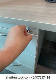 Closeup of hand locking/unlocking file cabinet and desk drawers with key.