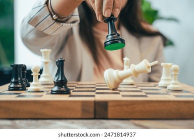 The close-up of a businesswoman’s hand making a checkmate move on a chessboard. The background shows an office setting, emphasizing the parallel between chess strategy and business acumen.
