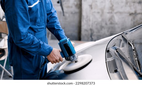 Close-up hand male mechanic wearing suit for working in garage for safety in risky work, mechanic standing using polishing machine scrub surface car that comes garage make new color. - Powered by Shutterstock