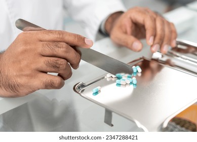 Closeup hand of male pharmacist counting and arrange pills on qualified stainless counting tray with spatula in pharmacy. Pharmacist prepare medication in stainless tray by prescription at drugstore. - Powered by Shutterstock