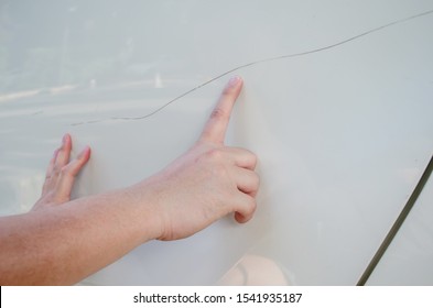 Close-up Of A Hand Man Looking For Scratches On His White Car, Hand Pointing At Dent On His White Car, Car Care And Protection Concept.
