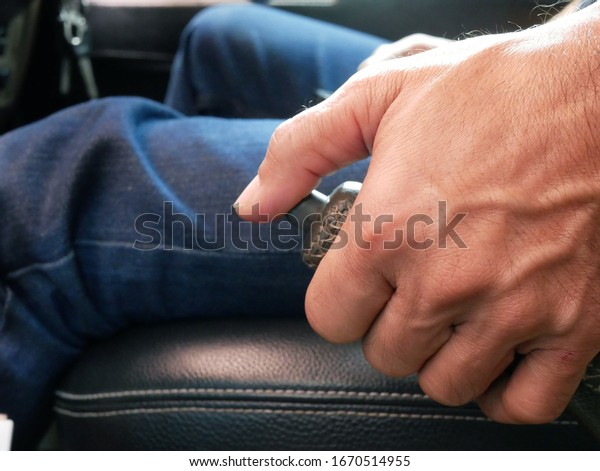 closeup of hand\
man pulling hand brake in\
car.