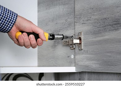 Primer plano de un hombre de mano con tornillos destornilladores en los estantes de la cocina. Montaje de muebles para cocina casera. 