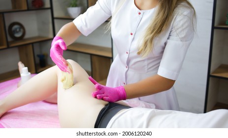 Close-up Of The Hand Of The Master Who Applies Sugar Paste On The Client's Thigh