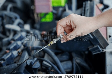 Close-up of a hand of mechanic pulling an engine oil dipstick to inspect oil level, highlighting vehicle maintenance and engine care in a workshop environment