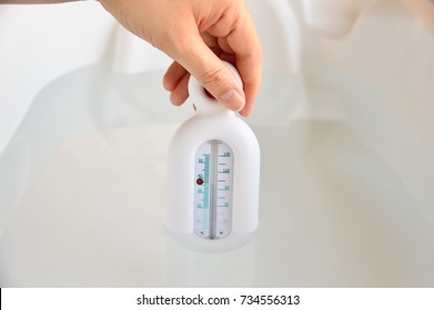 Close-up Of Hand Of A Mother Checking The Water Temperature Of The Child's Bathtub