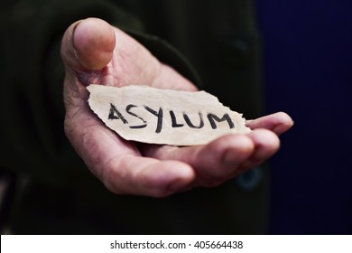 closeup of the hand of an old man with a piece of paper with the word asylum, with a dramatic effect