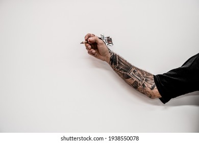 Close-up Of Hand Old-fashioned Hipster Tattoo Artist Holding Tattoo Machine On A White Background.