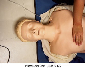 Close-up Of A Hand On A CPR Practice Dummy On The Floor With Mat For EMT, Paramedic, And Emergency Medicine Education. Healthcare Training Concept.