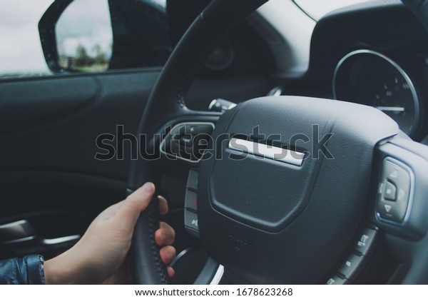 Closeup of a\
hand on the steering wheel of a\
car