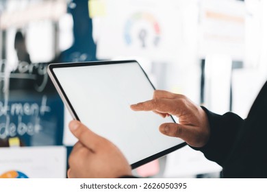 Close-up of hacker’s hand operating tablet, preparing to deploy malware or extract sensitive data, surrounded by corporate visual notes and confidential analytics