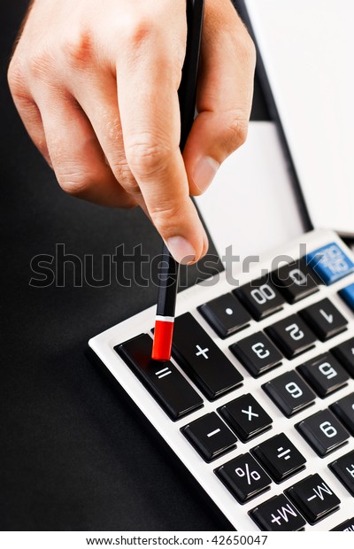 Closeup of a hand with pencil pressing equal\
button on calculator