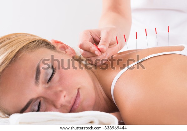 Closeup of hand performing acupuncture therapy on\
customer\'s back at\
salon