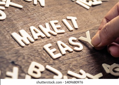 Closeup hand place the wood letters on wood table as the phrase MAKE IT EASY - Shutterstock ID 1409680976