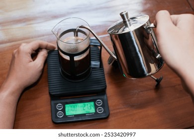 Closeup a hand Pouring the hot water into coffee powder on the french press glass, Brewing method French press coffee maker. - Powered by Shutterstock