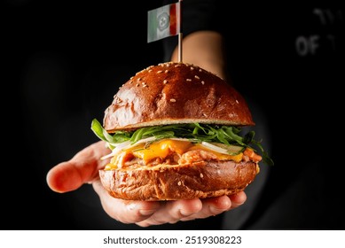 A close-up of a hand presenting a gourmet burger with a flag toothpick, sesame bun, fresh greens, and a fried egg on top. Perfect for food photography, restaurant menus, or culinary blogs. - Powered by Shutterstock